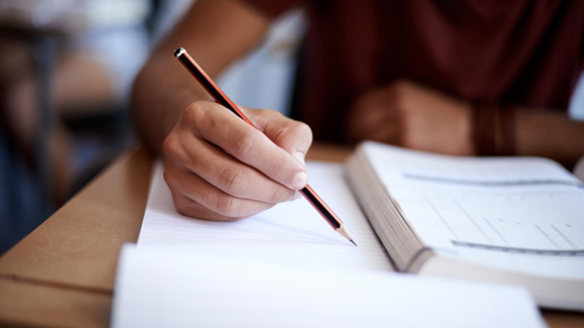 Closeup shot of a young man writing on a note pad